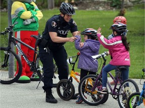 Windsor Police Const. Cealia Gagnon, left, helps young cyclists with hand signals during a bike safety clinic hosted by Downtown Windsor Community Collaborative and Free Wheeling at Bruce Avenue Park Sunday May 15, 2016.