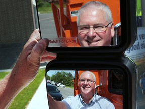 The County of Essex in partnership with the Canadian Automobile Association and Bike Windsor Essex launched the "Watch for Bikes" decal program on Tuesday, May 31, 2016, at the Essex Civic Centre. Tom Bateman, director of transportation services for the county is reflected in a mirror of county truck after installing the decal. (DAN JANISSE/The Windsor Star)