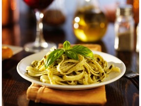Italian fettuccine in basil pesto sauce on dinner table at night. Photo by Getty Images.