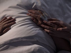 A daughter touches the hands of her ill mom.