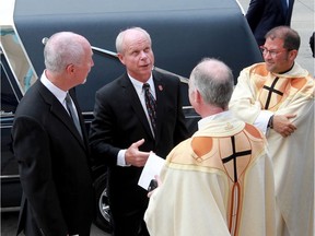 DETROIT, Michigan. June 15, 2016. Mark Howe, centre, looks to the sky while chatting with clergy of The Cathedral of the Most Blessed Sacrament on Woodward Avenue in Detroit following the funeral of Gordie Howe, Wednesday June 15, 2016.  Family friend Chris Winn, left, joined the conversation. (NICK BRANCACCIO/Windsor Star)