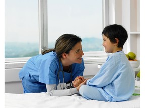 Doctor smiling with patient in hospital bed. Photo by Getty Images.