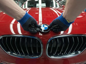 A worker fixes the logo of German car maker BMW on a BMW car at the company's plant this March 2014 file photo.