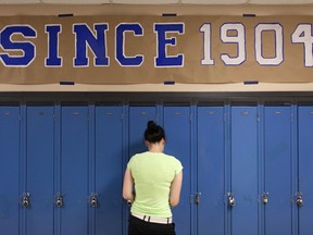 A Harrow District High School student gets into her locker under a 'Since 1904' sign, Thursday, June 16, 2016.