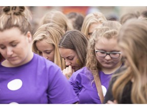 High school students bow their heads during rally in Woodstock, Ont. after they and hundreds of their classmates walked out of school Tuesday, June 7, 2016 to raise awareness of a suicide crisis which is gripping the small Ontario community.