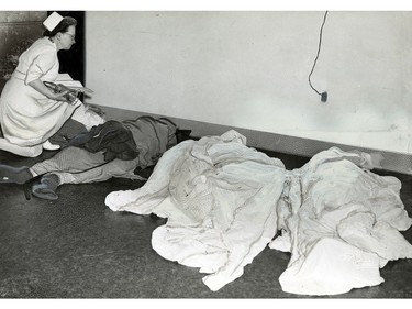 June 19, 1946: Evidence of the deadly tornado that struck the Windsor area on June 17, 1946 is shown as an official with Grace Hospital checks one of the five bodies for possible identification in a temporary morgue at the hospital.
