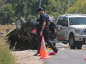 An Amherstburg police officer walks near the scene of a rollover crash on County Road 50 in Amherstburg on June 17, 2016.