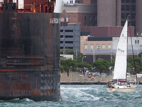 A sail boat is dwarfed by a freighter as they move along the Detroit River near downtown Windsor, ON. on Monday, June 6, 2016.