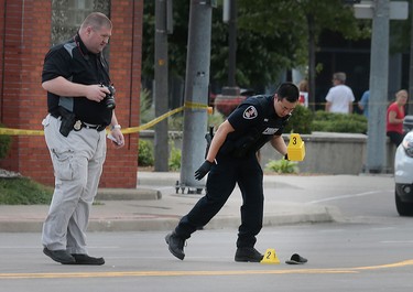 Windsor Police officers investigate the scene of a shooting near a Tim Hortons at the corner of Wyandotte St. E. and Walker Rd. on Wednesday, June 22, 2016, in Windsor, Ont.
