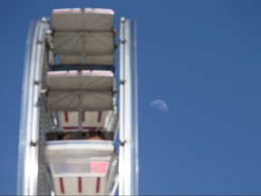 A daylight moon is pictured next to the ferris wheel on a bright sunny day at the LaSalle Strawberry Festival, Sunday, June 12, 2016.