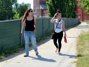 Danielle Renaud, 24, left, and Maria Borges, 28, walk on the beach side of a chain link fence which was installed to deter gawkers on Riverside Drive East at Sand Point beach June 03, 2016.