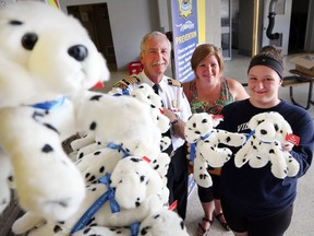 Windsor Fire Chief Bruce Montone, left, accepts 138 stuffed dalmatian dogs from Villanova Catholic High School teacher Jolene Coste, and Grade 12 student Caley Hewitt at Windsor Fire Service headquarters in Windsor on June 27, 2016. Villanova students raised $1,500 to buy the 138 stuffed toys that will be given to children at emergencies.