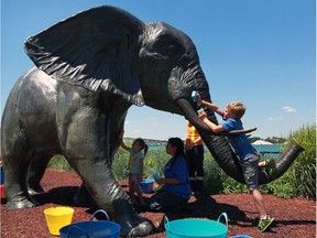 Logan Conrod, 8, right, join with others to give Tembo, the elephant sculpture, a bath at Windsor Sculpture Park on the riverfront Thursday June 30, 2016.