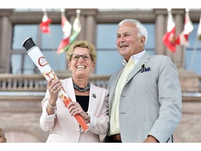 In this file photo, Ontario Premier Kathleen Wynne receives an honourary Pan Am Games torch from former Ontario premier David Peterson, chair of the board that organized the Toronto 2015 Pan Am/Parapan Am Games during a ceremony at Queen's Park in Toronto, Thursday, July 9, 2015.