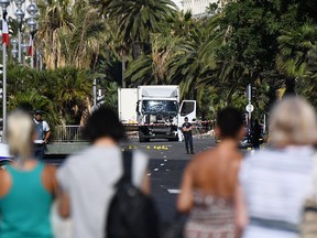 People look at a truck stand guarded by the police on the Promenade des Anglais seafront in the French Riviera town of Nice on July 15, 2016, hours after it drove into a crowd watching a fireworks display. An attack in Nice where a man rammed a truck into a crowd of people left 84 dead and another 18 in a "critical condition", interior ministry spokesman Pierre-Henry Brandet said Friday. An unidentified gunman barrelled the truck two kilometres (1.3 miles) through a crowd that had been enjoying a fireworks display for France's national day before being shot dead by police.