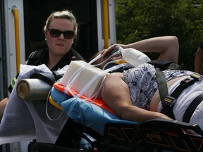 A paramedic assists an injured pedestrian after three people were struck by a car on Notre Dame Street in Belle River on July 29, 2016.