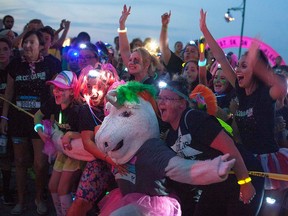 Runi the Runicorn poses for a photo with people taking part in The Color Run Night 5k along Windsor's waterfront Saturday evening, July 23, 2016.