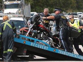 Officers with the Ontario Provincial Police help a flat bed operator load a damaged motorcycle on Monday, July 25, 2016 in Tecumseh, Ont.