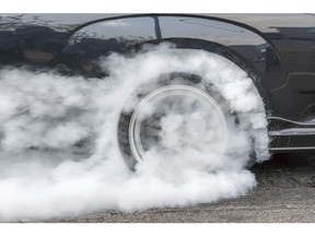 Drag racing car burns rubber off its tires in preparation for the race. Photo by Getty Images.