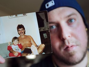 Brian Clark, 31, holds an old photo of himself on his father James Clark's knee at his Windsor home on Tuesday, July 12, 2016. James Clark was killed when his motorcycle collided with a semi-truck on Monday, July 11, 2016 in Tecumseh.