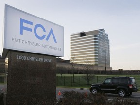 A vehicle moves past a sign outside Fiat Chrysler Automobiles world headquarters in Auburn Hills, Mich.
