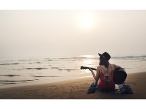 Playing guitar and writing music on the beach. Photo by Getty Images.