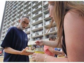 James McCarte, 59, who lives at the Ouellette Manor gets a hand with his barbecue lunch on Thursday, July 28, 2016, from Amanda LaFrance of the Community University Partnership organization.