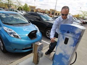 Sean Hart charges his new Nissan Leaf electric car at a charging station at the Windsor Crossing Outlet in Windsor on Monday, May 13, 2013.