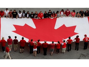 WINDSOR, ONT. May 18, 2015 -- Canadian flag loaned from Windsor Parade Corp. and measuring 30-feet by 60-feet, is displayed at the foot of Ouellette Avenue part of a demonstration by Great Canadian Flag Project group headed by Peter Hrastovec and Michael Beale, shown bottom left, Monday May 18, 2015.  About 100 volunteers helped with the flag event held in conjunction with Windsor's 123rd birthday celebration on the riverfront.  (NICK BRANCACCIO/The Windsor Star).