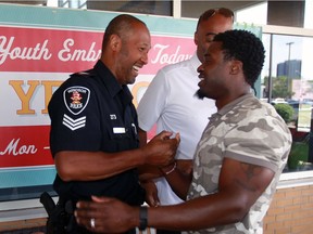 Windsor police Sgt. Wren Dosant, left, Windsor Express head coach Bill Jones, behind, greet former NFL defensive back O.J. Atogwe during opening day celebrations of Youth Embracing Today's Youth Centre (Y.E.T.Y.) at Windsor Water World Monday July 4, 2016.