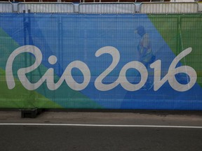 A volunteer walks behind a barrier printed with the Rio2016 logo inside Olympic Park ahead of the upcoming Summer Olympics in Rio de Janeiro, Brazil, on Aug. 2, 2016.