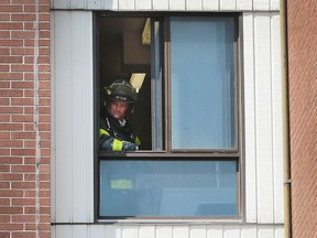 A Windsor firefighter looks out of a fourth floor apartment window on Aug. 4, 2016 at the Wheelton Manor apartment building at 333 Glengarry Ave. Crews quickly put out a fire in the unit that was intentionally set.