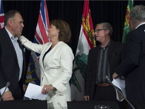 British Columbia Premier Christy Clark, centre, gives Yukon Premier Darrell Pasloski a hug as Saskatchewan Premier Brad Wall looks on following a meeting of Premiers in Whitehorse, Yukon, Friday, July, 22, 2016.