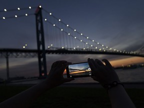 Wan Xu, an international student from China studying at the University of Windsor, takes a photo of the Ambassador Bridge at sunset, Friday, August 26, 2016.