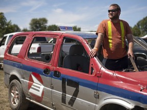 Matt Michaud, 23, stands in his Canada Post van before competing in the Comber Fair Demolition Derby, Sunday Aug. 7, 2016.