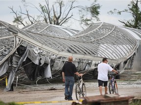 A couple of men check out the damage to greenhouses at Yoder Canada Ltd., in Leamington where a tornado blew through June 6, 2010. The business is located on Seacilff Drive.