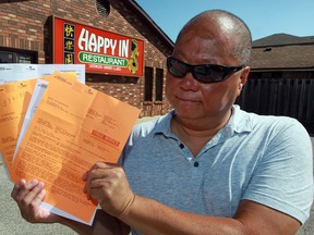 Steve John of Happy In Restaurant is concerned about the high cost of hydro for his Leamington dining room. He holds up some of the power bills on Aug. 26, 2016.