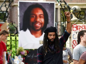 Tyler Clark Edwards of St. Paul raises his fist in the air in front of a large photo of Philando Castile, as protesters encamped in front of the Governor's residence in St. Paul, Minn. pack up their belongings Tuesday, July 26, 2016. Police have arrested an unknown number of protesters in front of the governor's mansion on St. Paul's Summit Avenue. Demonstrators have been camping outside the governor's residence since early July 7, a day after the shooting of Philando Castile, who was killed by a St. Anthony police officer during a traffic stop. (Scott Takushi/Pioneer Press via AP) ORG XMIT: MNPAU103