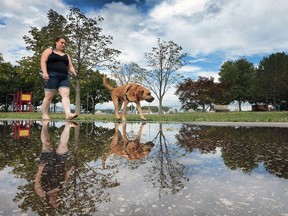 Allison Peters and her dog Garem are reflected in a puddle at the Brumpton Park in Windsor Tuesday, Aug. 16, 2016.