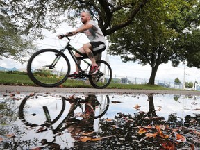 A cyclist is reflected in a puddle along the Ganatchio Trail in Windsor on Tuesday, August 16, 2016. The region finally received some much needed rainfall.