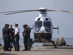 OPP officers hold a meeting next to an OPP helicopter at the end of the Colchester Harbour Marina, Monday, July 31, 2016, as recovery efforts continue after a woman went missing in Lake Erie.