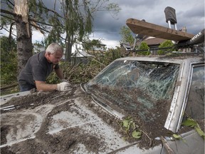 David Andrukonis cleans up debris off his Oldsmobile Cutlass from a tornado at his house on Riberdy Road where he's lived for 27 years with his wife Debra Andrukonis, Thursday, August 25, 2016.