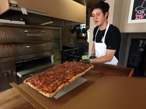 Riviera Pizza owner Jacob Dunn pulls a freshly made pizza out of the oven at their Ottawa Street location on Thursday, August 18, 2016.