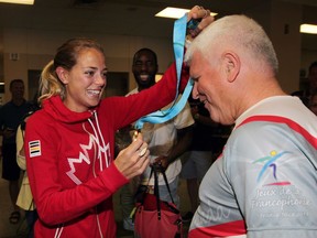 Melissa Bishop arrives at Windsor airport and gives her coach Dennis Fairall the gold medal she won in the 800 metres at the Pan American Games on July 23, 2015.
