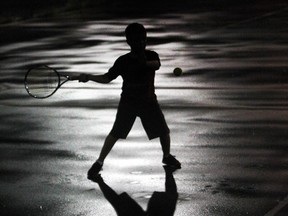 Damian Gorski, age 8, is silhouetted against a wet tennis court at Central Park  on Aug. 12, 2016 in south Windsor.     Gorski and other junior players continued to work out during a brief rain shower.