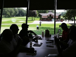 Patrons at Roseland Golf and Curling Club have drinks in the restaurant overlooking the putting green.