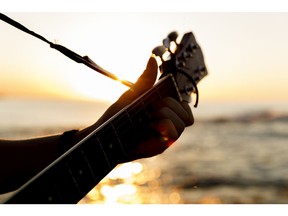 Man playing a guitar at sunset. Photo by Getty Images.