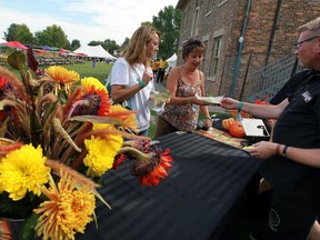 Tammy Teves, left, and Veronique Peladeau are served fish tacos from Troy Loop of Black Jack's during the opening of Windsor-Essex Harvest Festival at Fort Malden Friday, September 9, 2016.