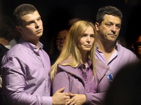 In this photo taken on  Friday, Sept. 12, 2014, C.J. Bernauer, left, and parents Kimberly and Christian Bernauer are shown during a vigil for their sister and daughter Emily, who was killed in a car accident the week before.