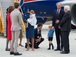 Canadian Prime Minister Justin Trudeau, centre, kneels to talk to Prince George as his father Prince William, The Duke of Cambridge, speaks with the Governor General David Johnston, right,  and Catherine, The Duchess of Cambridge holds their daughter Princess Charlotte upon arrival at 443 Maritime Helicopter Squadron base on Sept. 24, 2016, in Victoria, B.C.